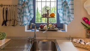 A kitchen with a window, a sink, and various kitchen utensils hanging on the wall. - Cascina Arcangelo Raffaele, Apartment Gabriele (VERDUNO)