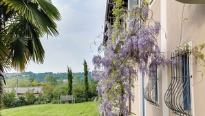 A building with a garden, a bench, and a view of the countryside. - Cascina Arcangelo Raffaele, Apartment Gabriele (VERDUNO)