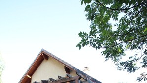 A covered outdoor seating area with tables and chairs, a pergola structure, and a building with wooden shutters. - Exceptional Cyclist Friendly House, Bourg d'Oisans (Les Bords de Rive)