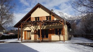 A chalet with a wooden facade, a covered porch, and a mountain backdrop. - Exceptional Cyclist Friendly House, Bourg d'Oisans (Les Bords de Rive)