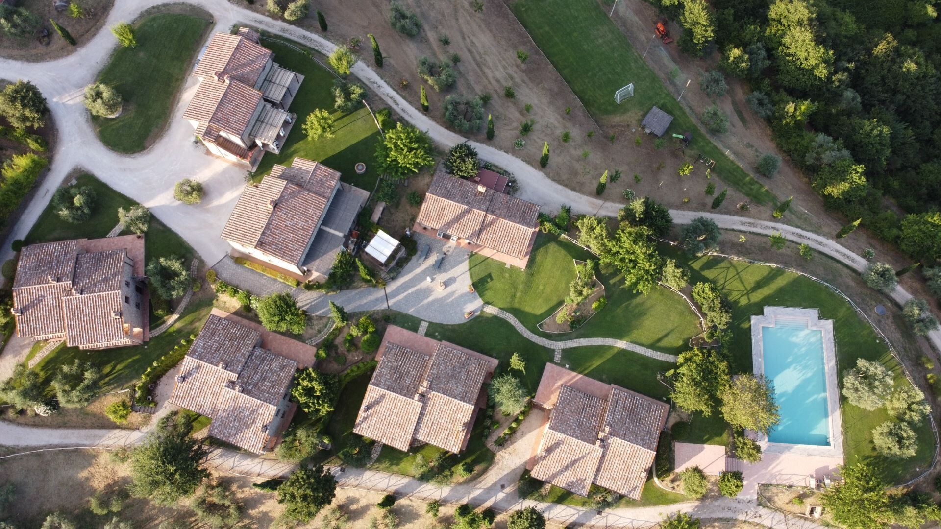 An aerial view of a residential area with multiple houses, a swimming pool, and well-maintained lawns.