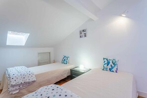 Cozy retreat with two single beds, a nightstand, and a sloping ceiling with exposed beams.