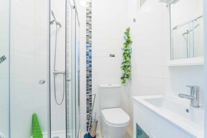 Bathroom features a glass-enclosed shower, toilet, and sink with a mirror.