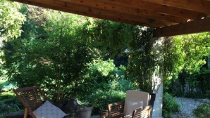 An outdoor patio with wooden furniture, including chairs and a table, under a wooden pergola. - Large & beautiful villa on large landscaped fenced garden, large secure pool. (Montpellier)