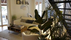 A living room with a sofa, coffee table, and potted plants. - Large & beautiful villa on large landscaped fenced garden, large secure pool. (Montpellier)