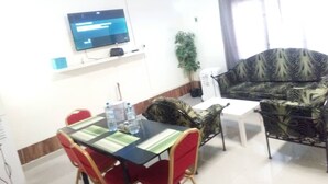 Un salon moderne avec un téléviseur à écran plat, une table à manger avec des chaises, un canapé et une plante en pot.