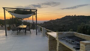 An outdoor patio with a pergola, dining table, chairs, and a barbecue grill.