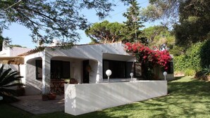 Une maison moderne dotée d’un patio couvert, d’un petit jardin et d’une façade blanche.