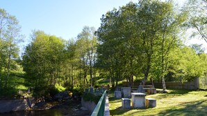 A serene park with a river, benches, and a bridge. - Mountain Homes Gralheira - Mountain House (Cinfães)