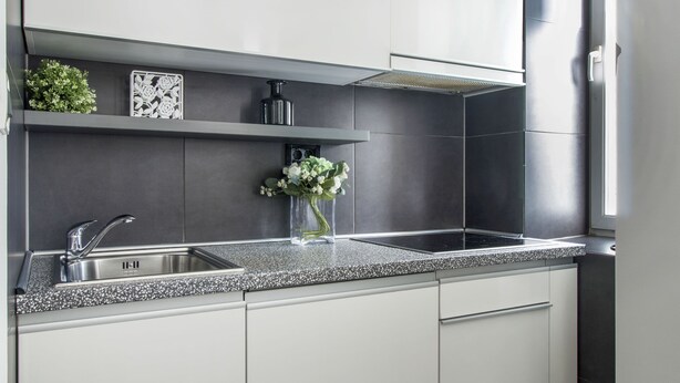 Eine moderne Küche mit einer Granit-Arbeitsplatte, einer Edelstahl-Spüle und weißen Schränken.