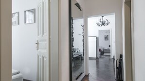 Ein Flur mit Holzboden, einem großen Spiegel und einer Chandelier.