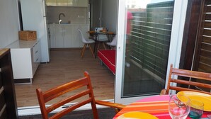 Une cuisine compacte avec des meubles blancs, un réfrigérateur et un coin repas avec une table dressée pour deux personnes.