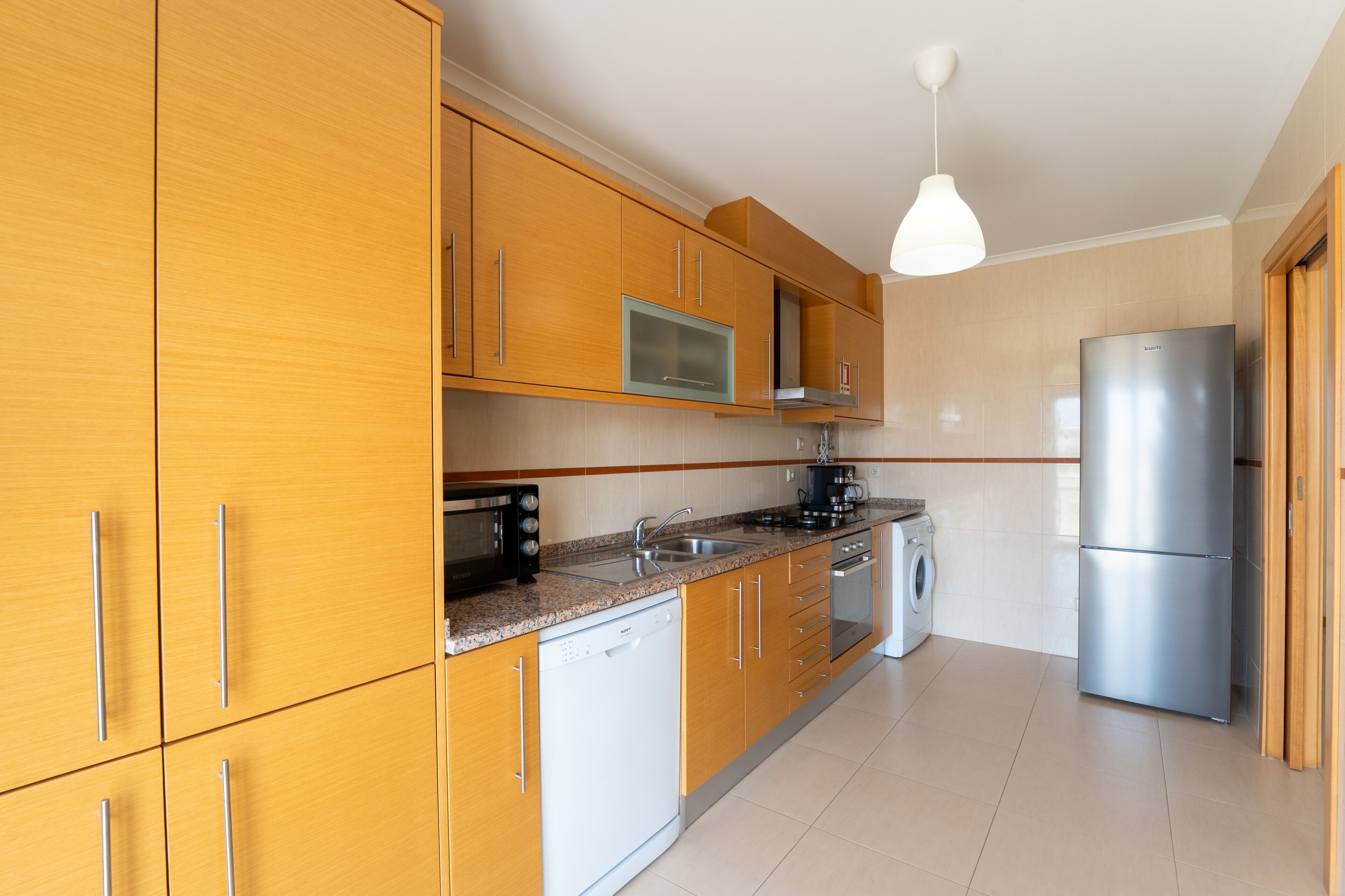 Una cocina moderna con armarios de madera, electrodomésticos de acero inoxidable y un horno empotrado.