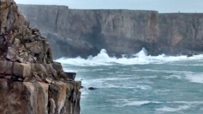 A coastal cliff with waves crashing against it.