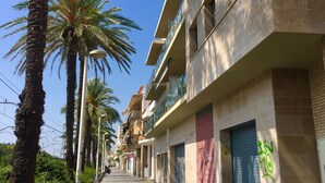 Una fila di edifici a più piani con balconi, palme e cielo sereno.