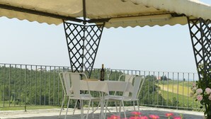 A covered outdoor seating area with a table and chairs, overlooking a scenic landscape. - LECCINO ROOM at Agriturismo MUSIGNANO (cerreto guidi)