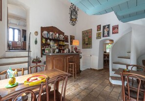 Una cocina rústica con muebles de madera, una zona de bar con botellas y una escalera que sube a otra habitación.