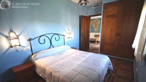 Une chambre à coucher comprenant un lit, des tables de chevet, une armoire et une porte donnant sur une autre pièce.