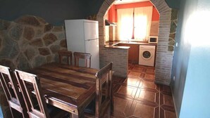 Une cuisine compacte avec un mur en pierre, une table à manger en bois et un lave-linge.