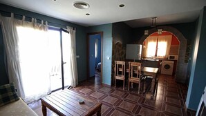Un espace de vie compact comprenant un coin repas, une kitchenette et une porte donnant sur une autre pièce.