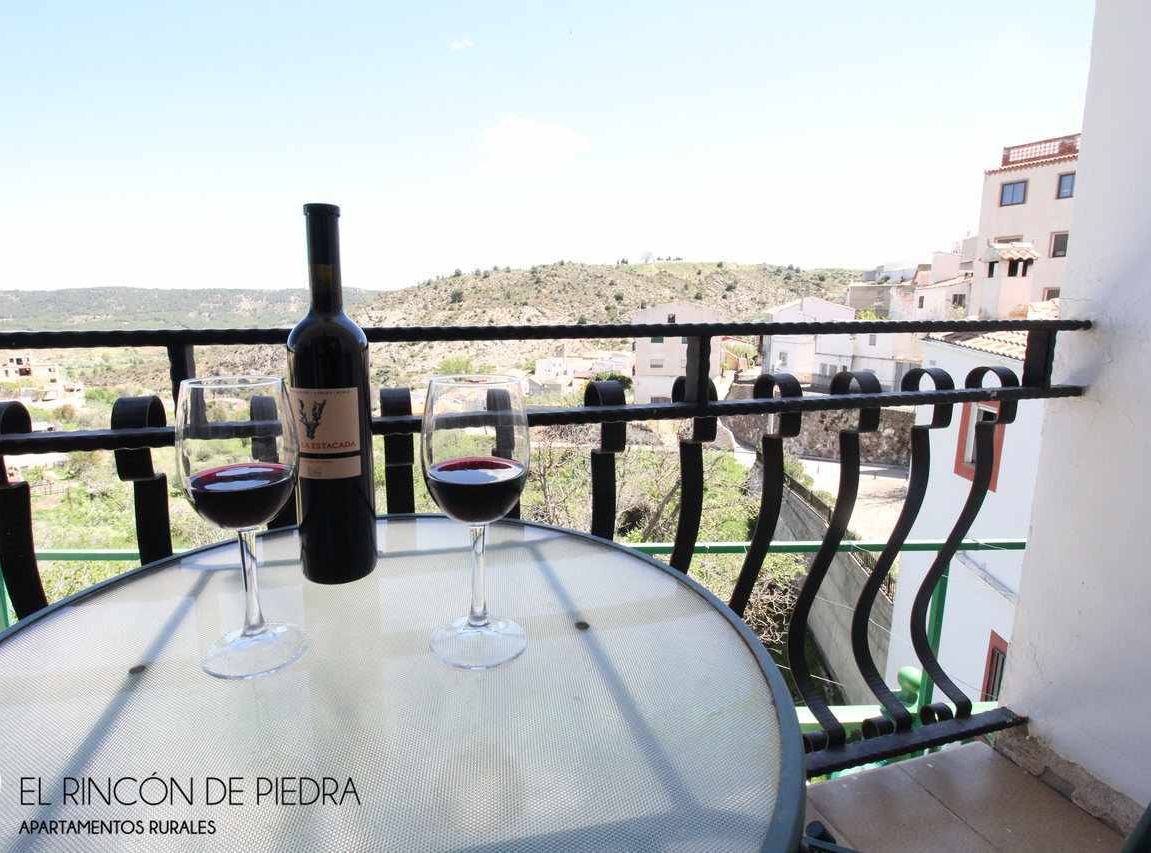 A balcony with a table, two wine glasses, and a bottle of wine.