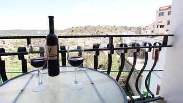 Un balcon avec une table, deux verres à vin et une bouteille de vin.