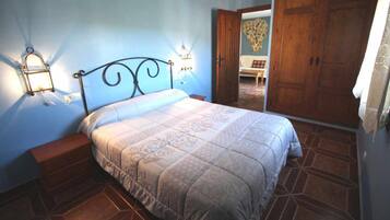 Une chambre à coucher comprenant un lit, des tables de chevet, une armoire et une porte donnant sur une autre pièce.
