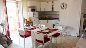 A compact kitchen with white cabinets, a microwave, and a clock on the wall.