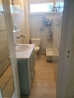 Un baño con lavamanos blanco, inodoro y zona de ducha.