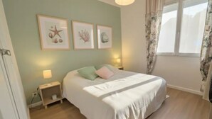 A bedroom with a bed, a nightstand, a lamp, and framed pictures on the wall.
