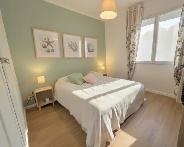 A bedroom with a bed, a nightstand, a lamp, and framed pictures on the wall.