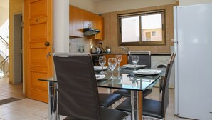Eine moderne Küche mit Essbereich, ausgestattet mit einem Glastisch, Stühlen und einem weißen Kühlschrank.