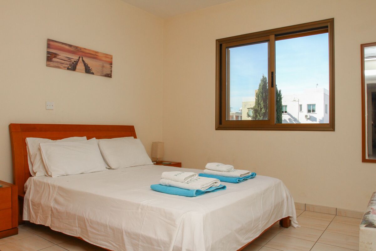 Ein Hotelzimmer mit einem Bett, einem Nachttisch, einem Fenster und einem Bild an der Wand.