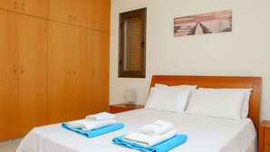 Una habitación de hotel con una cama, un armario de madera, una mesita de noche y un cuadro en la pared.