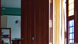 Un salon avec un canapé, une lampe, une armoire en bois et une fenêtre avec des rideaux.