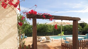 Un espace piscine agrémenté d’une pergola en bois, de chaises longues et d’une terrasse carrelée.