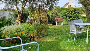 A garden with a table and chairs, surrounded by various plants and flowers. - ARTIST'S HOME, 5 MINUTES FROM THE SEA, VERY QUIET, TUCKED AWAY IN A LUSH GREEN SETTING. (Trégastel)
