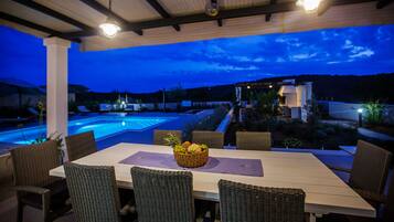 Enjoy a meal under the stars with a view of the pool and lush garden.