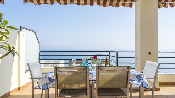 Una terrazza con un tavolo apparecchiato per due, vista mare.