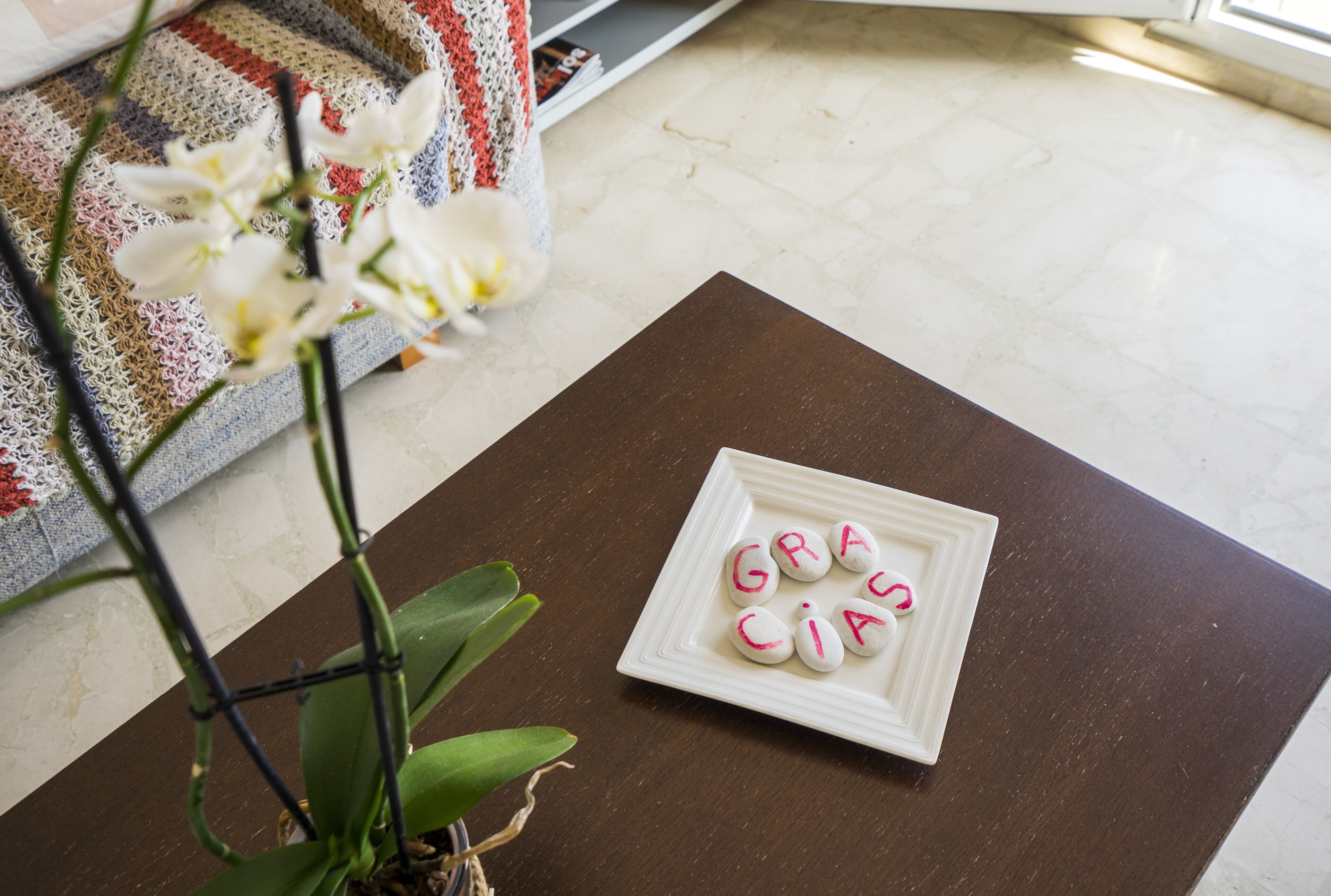 Une assiette blanche sur laquelle le mot « GRACIA » est écrit en rose, et qui est posée sur une table marron.