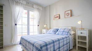 Una camera da letto con un letto, due comodini, una finestra con tende e una mensola a parete con fotografie.