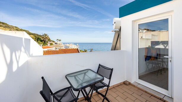 Un balcon avec une porte-fenêtre, une petite table et deux chaises.