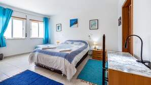 Une chambre à coucher avec un lit, des tables de chevet, un bureau et une chaise.