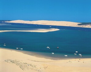 A coastal landscape with a sandy beach, clear blue waters, and boats.