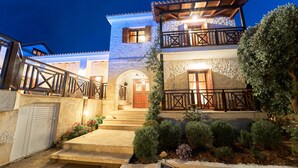 A two-story building with a stone facade, wooden balcony railings, and a well-lit entrance. - Lilas Luxury Villa, is a stone manor with its own private pool . (Zakynthos)