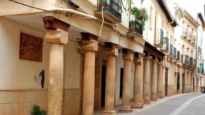 Files de columnes que sostenen la façana d'un edifici, amb plantes en testos a la planta baixa.