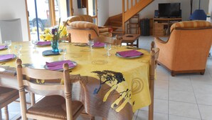 Een eetruimte met een tafel voor vier personen, omringd door houten stoelen. Een trap leidt naar een hoger gelegen niveau.
