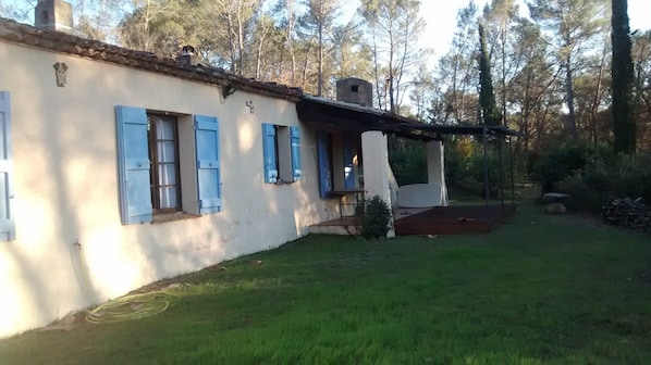 A rustic house with a sloped roof, blue shutters, and a small porch.
