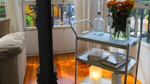 A room with a large window, a metal cart with books and a candle, and a vase with flowers. - Amazing Apartment in Regionalist building (Sevilla)