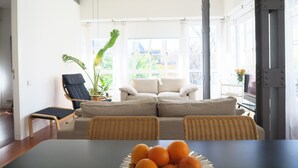 A modern living room with a sofa set, a dining table with oranges, and a potted plant. - Amazing Apartment in Regionalist building (Sevilla)